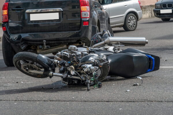 broken motorcycle closeup beside the car. an accident on the road in the city on a sunny day involving a motorcycle and a car.