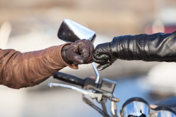 Arms of bikers touching with fists for greeting gesture, close-up view