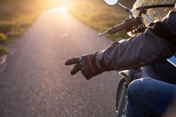 Close-up of a biker's hand showing the hand gesture of salute, the V gesture