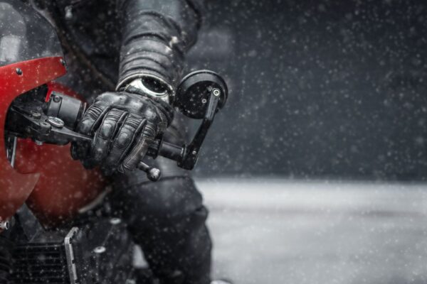 Hand in glove on motorcycle handlebar in winter, free space for insertion