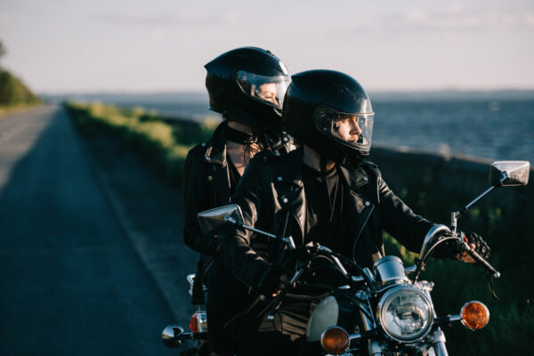 couple of bikers in helmets riding classical motorcycle on country road